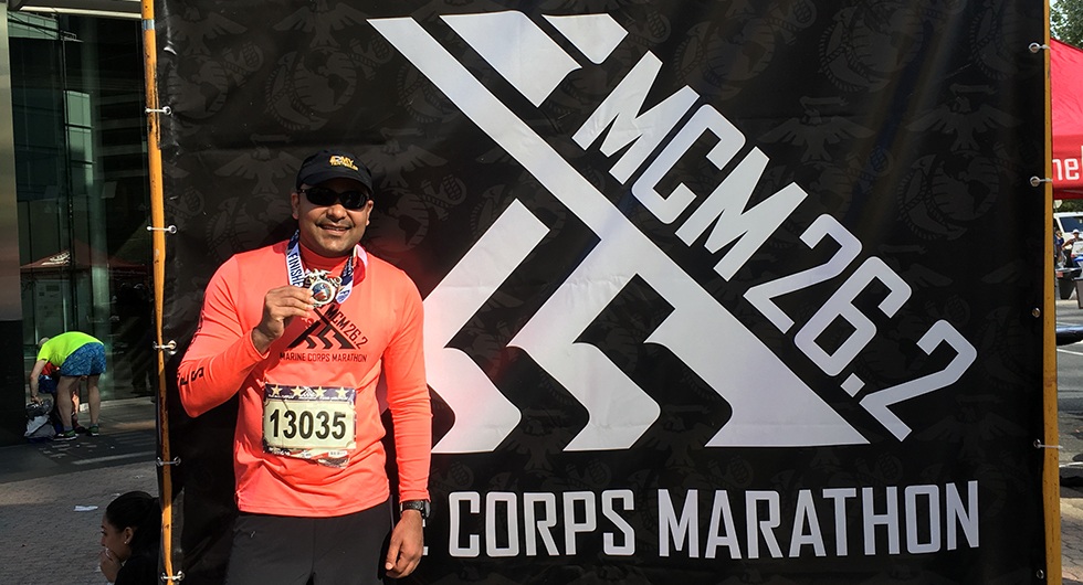 Doctor Goyal smiling and holding a medal after running a race
