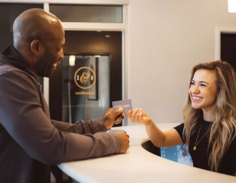 Man handing his credit card to woman behind reception desk