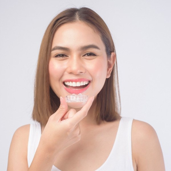 patient smiling while holding SureSmile aligner 