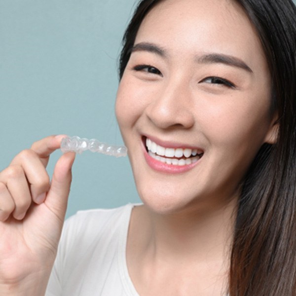 patient smiling while holding SureSmile aligner